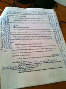 Photo of a typed manuscript page with extensive handwritten markups