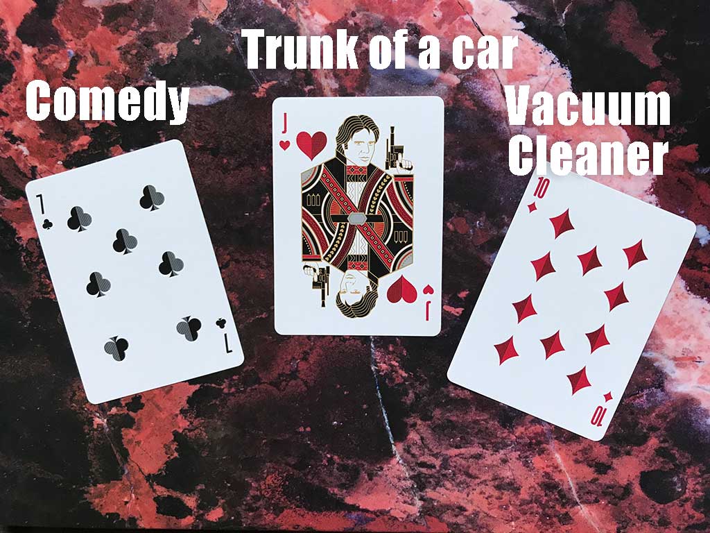 Flash Fiction Draw for July 2021: Three playing cards are shown, a 7 of clubs, a Jack of hearts, and a 10 of diamonds, with the words "comedy," "trunk of a car," and "vacuum cleaner" superimposed over the image.