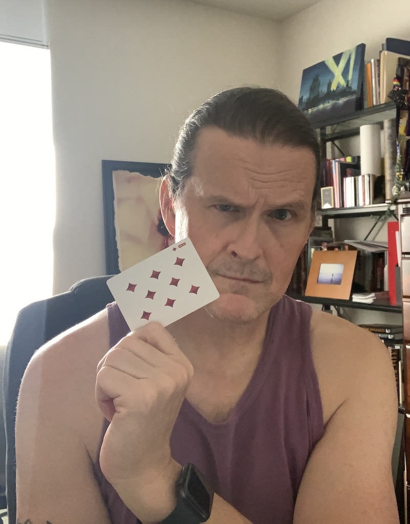Photo of a white male (me) holding a playing card, specifically the eight of diamonds.